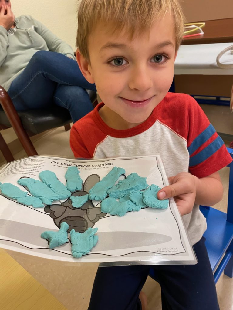 Young patient holding up his art project to the camera
