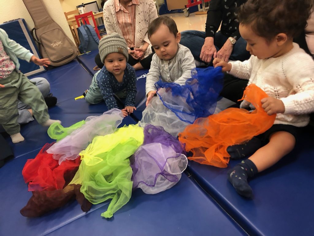 Young children together on a play mat with tissues playing together