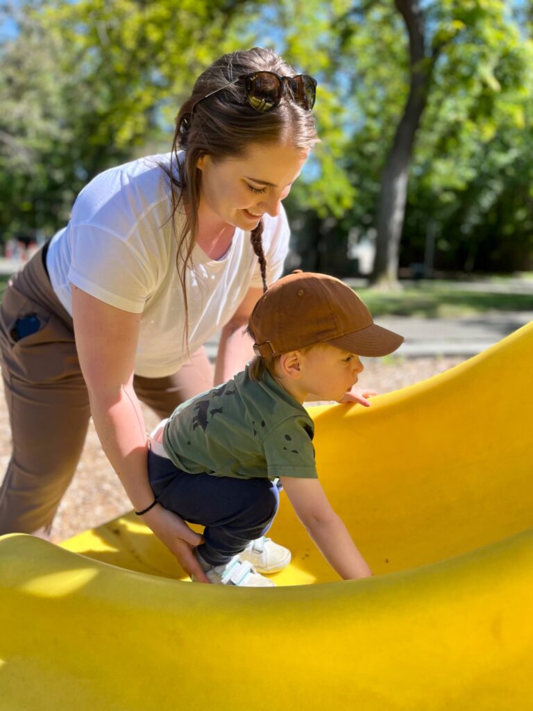 CTC therapist playing outside with a young patient on a yellow slide